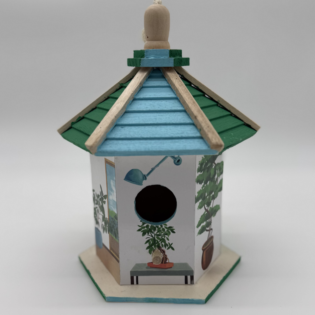 Decorative birdhouse with a green roof and white body featuring plants on a gray background