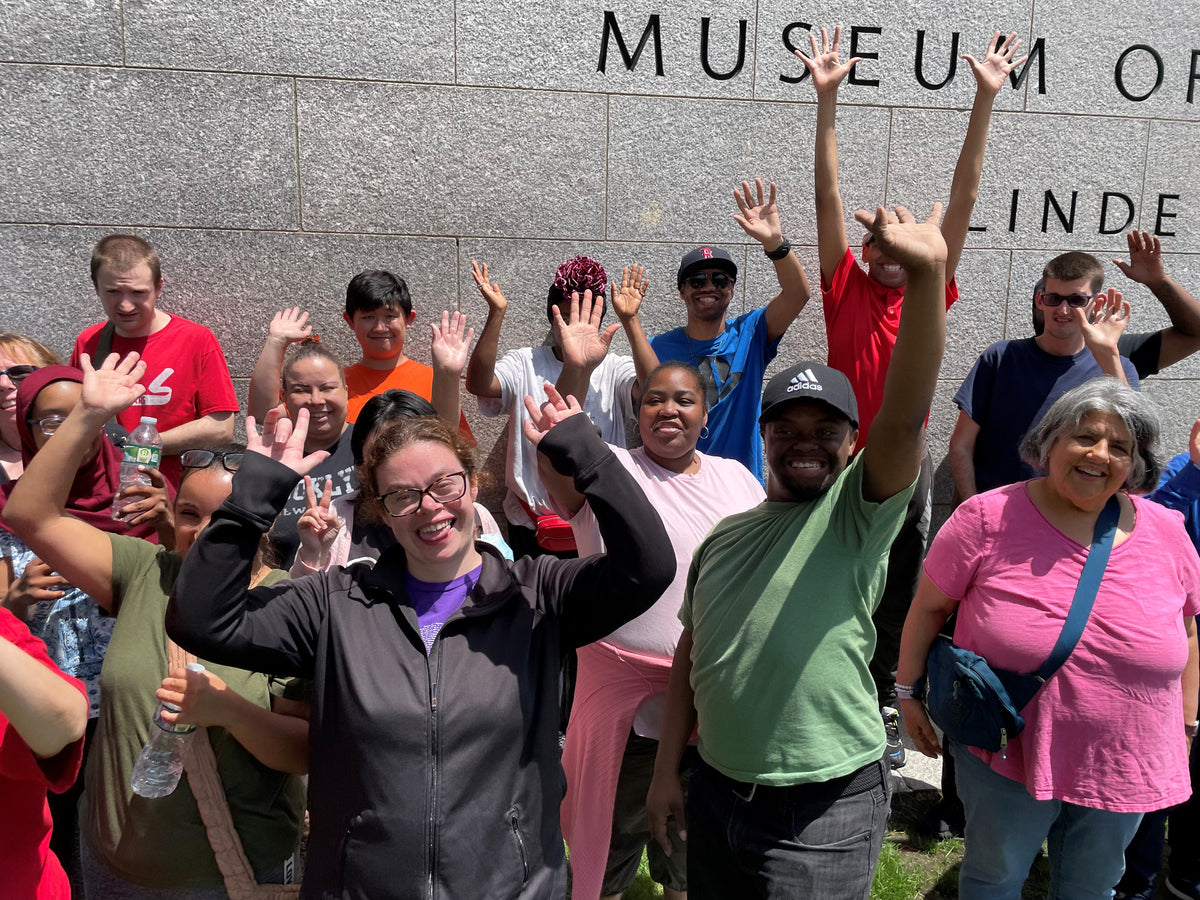 Group of people posing with raised hands in front of a building