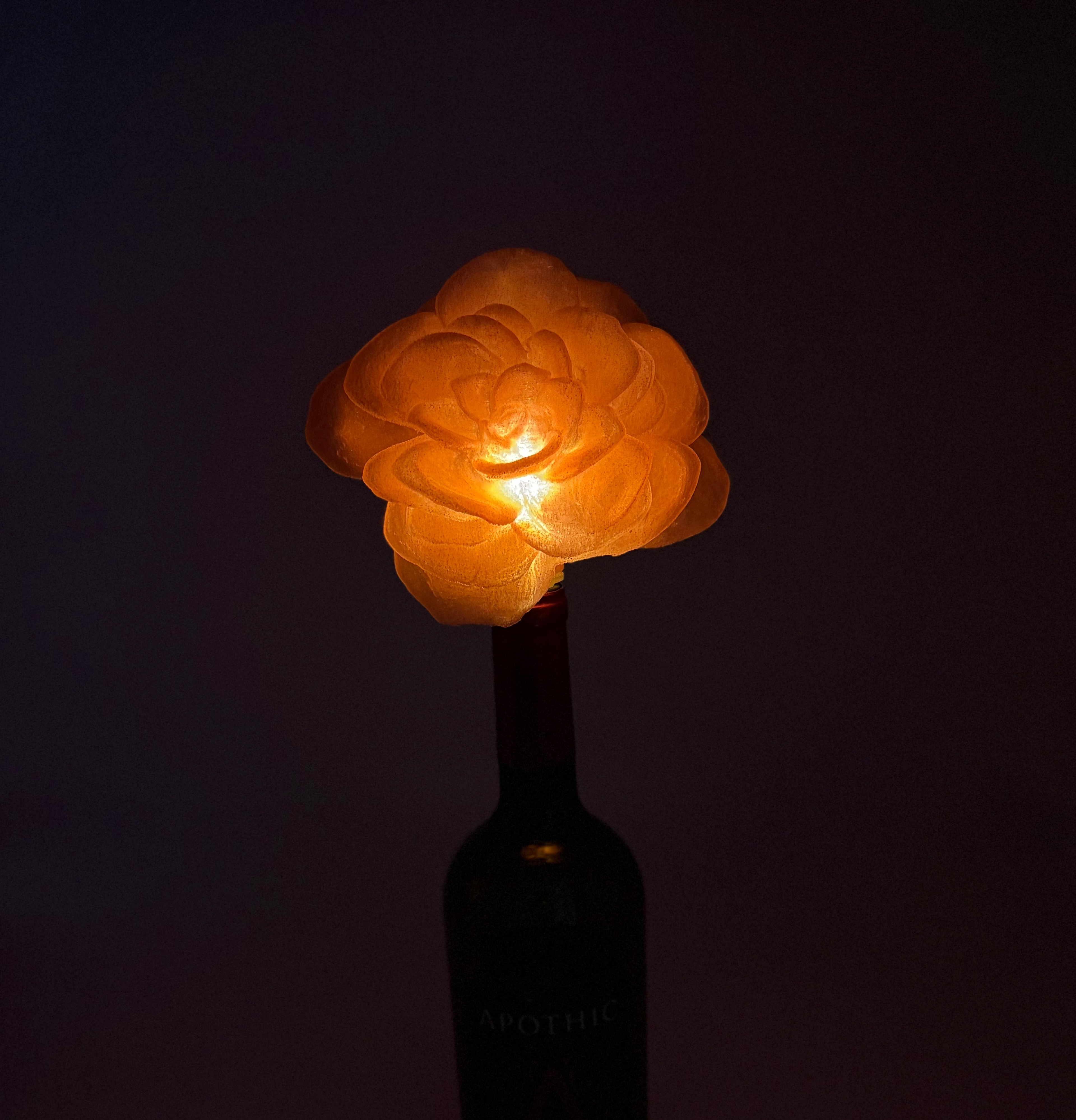Glowing flower-shaped bottle stopper on a dark background.