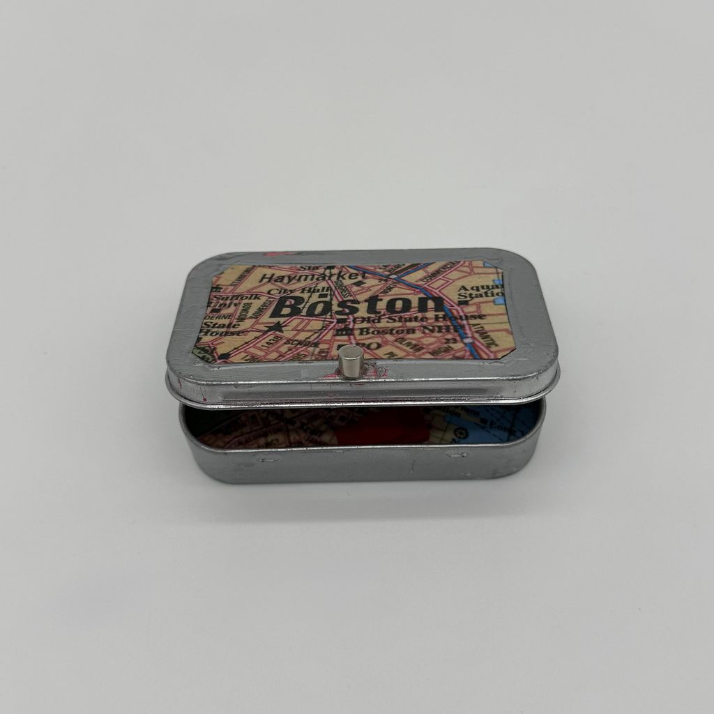 Small metal box with a decorative lid featuring "Boston" text and map graphics on a light gray background