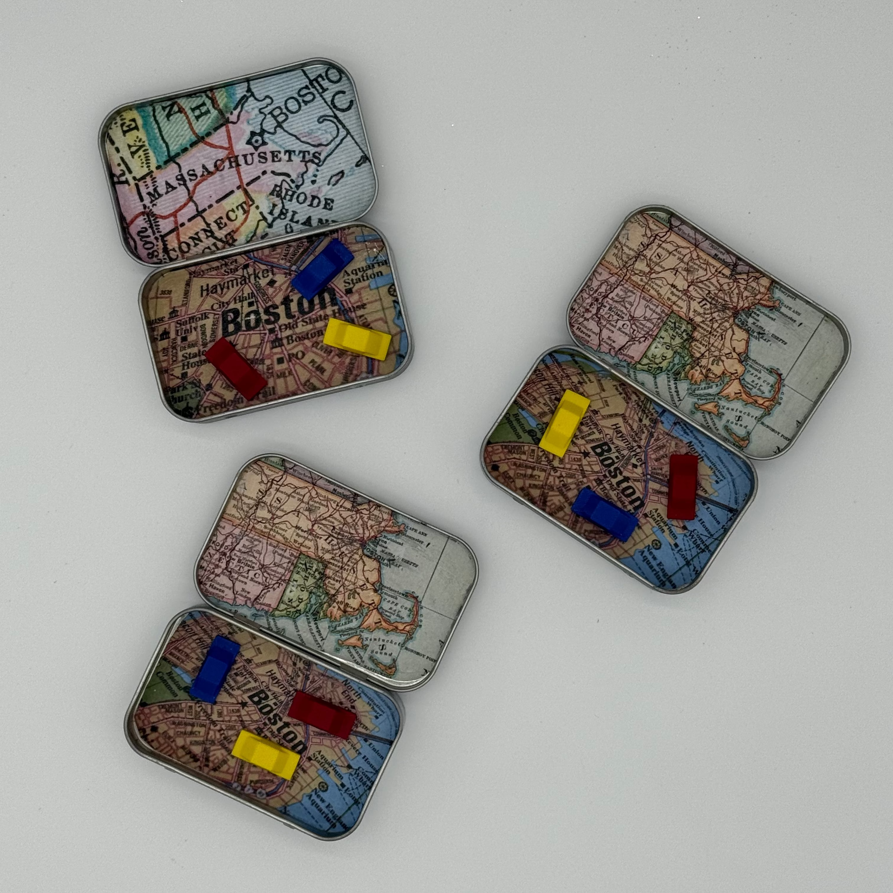 Three metal tins with miniature cars and map imagery on a white background