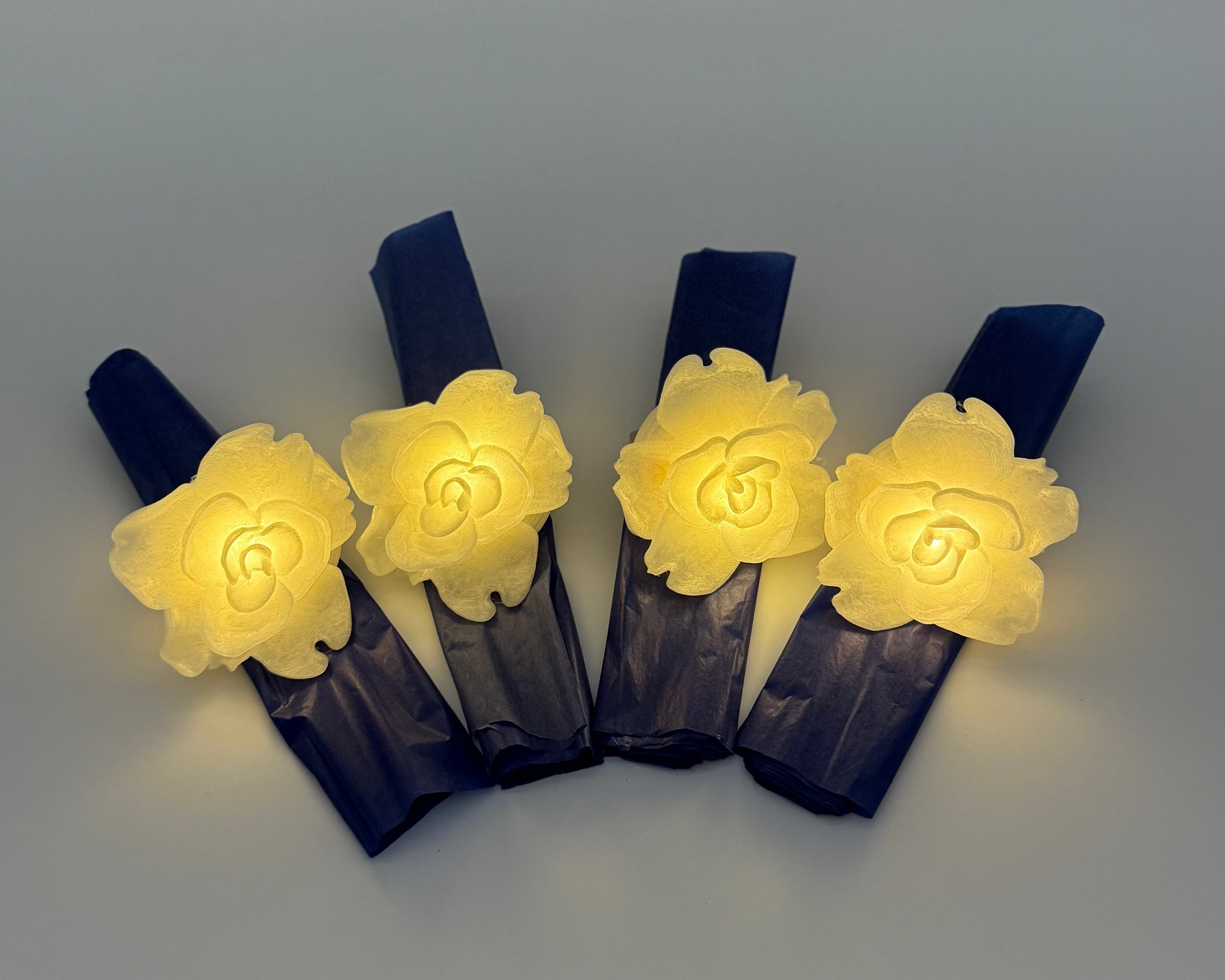 Four glowing white flower napkin holders on a light gray background