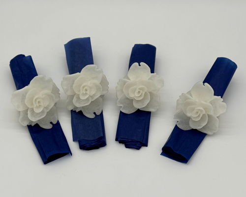 Four navy blue napkins with white floral decorations on a light gray background