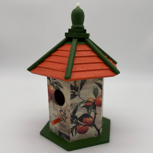 Decorative birdhouse with green roof and base on a white background