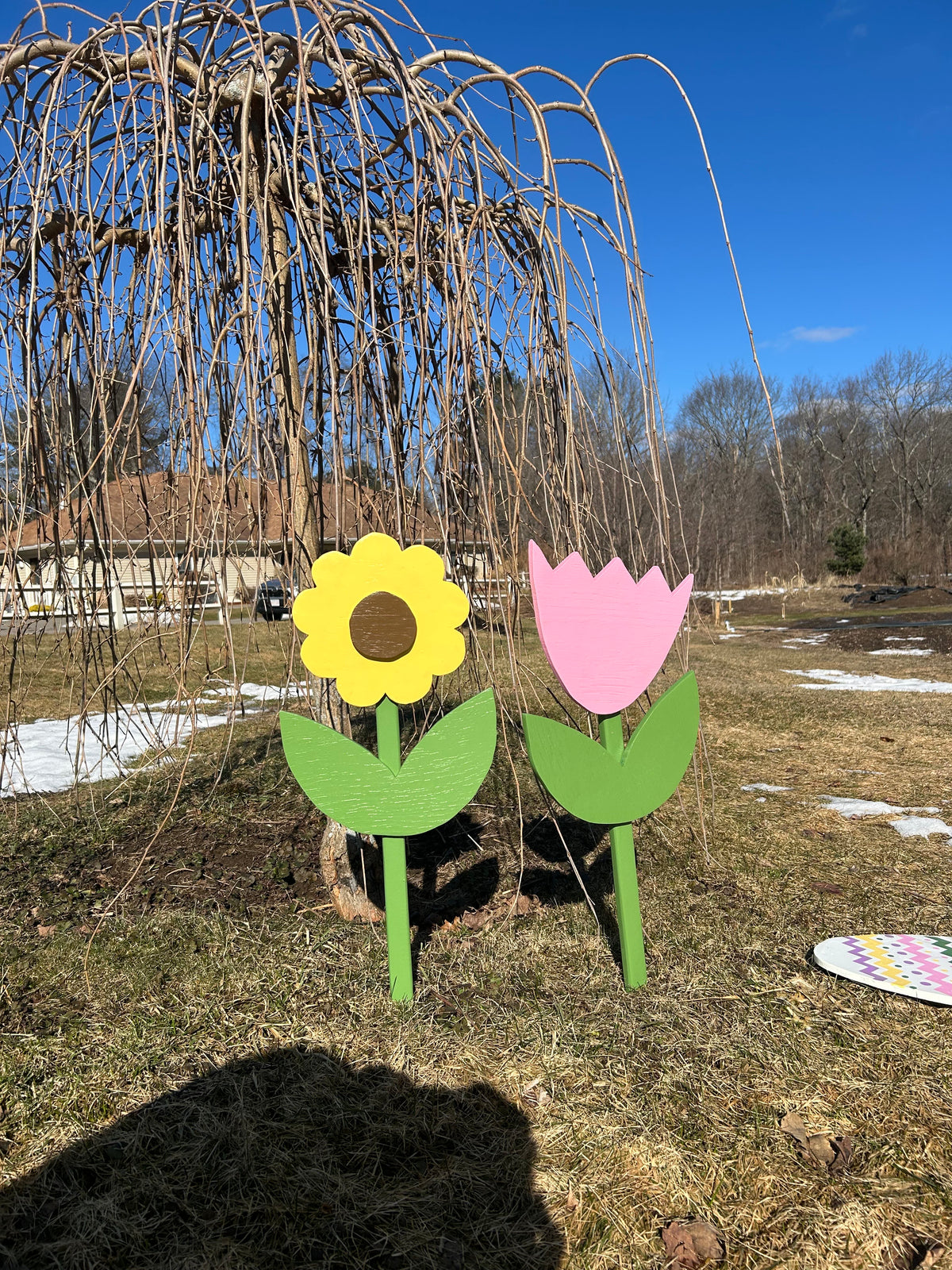 Colorful flower-shaped stakes in the ground with a clear blue sky in the background.