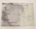 Banana cake recipe card on a textured glass cutting board