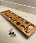 Wooden Mancala game set with colorful stones on a marble surface