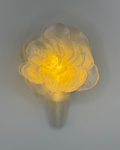 Floral-shaped light fixture with a yellow glow on a gray background