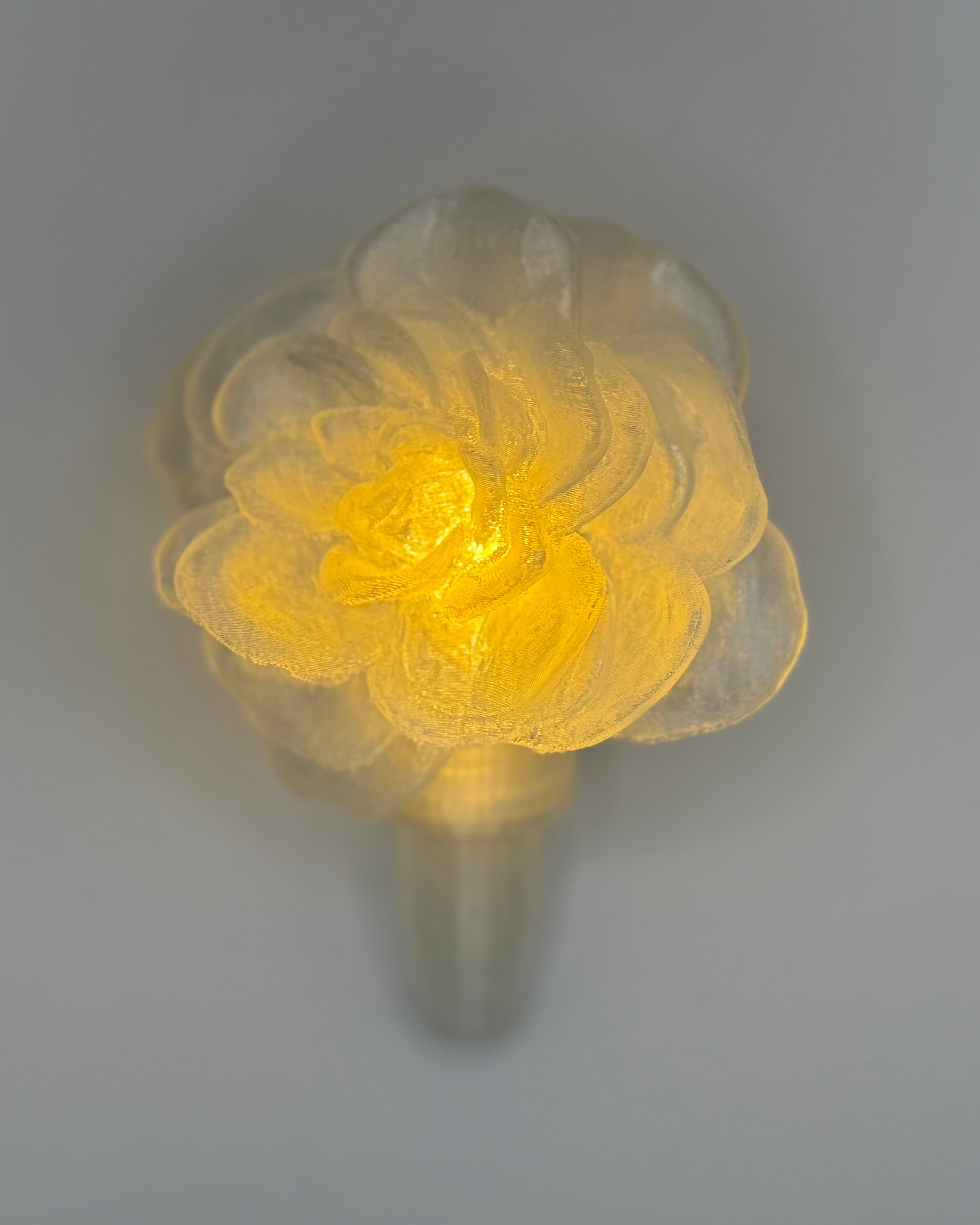 Floral-shaped light fixture with a yellow glow on a gray background