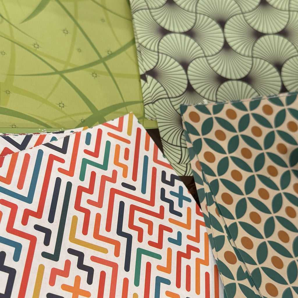 Four overlapping patterned fabric or paper swatches with geometric and floral designs in green, gray, white, red, orange, blue, and beige.
