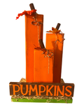 A decorative autumn pumpkin centerpiece with three stacked rectangular orange pumpkins, brown stems, faux leaves, twine details, and a wooden base that reads “PUMPKINS” in orange lettering, set against a plain white background.