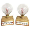 Two decorative light bulbs with clear glass globes, red heart-shaped filaments, and square wooden bases. The left base reads 'Light of my life' and the right base reads 'You light up my life' in black script with small red heart accents.