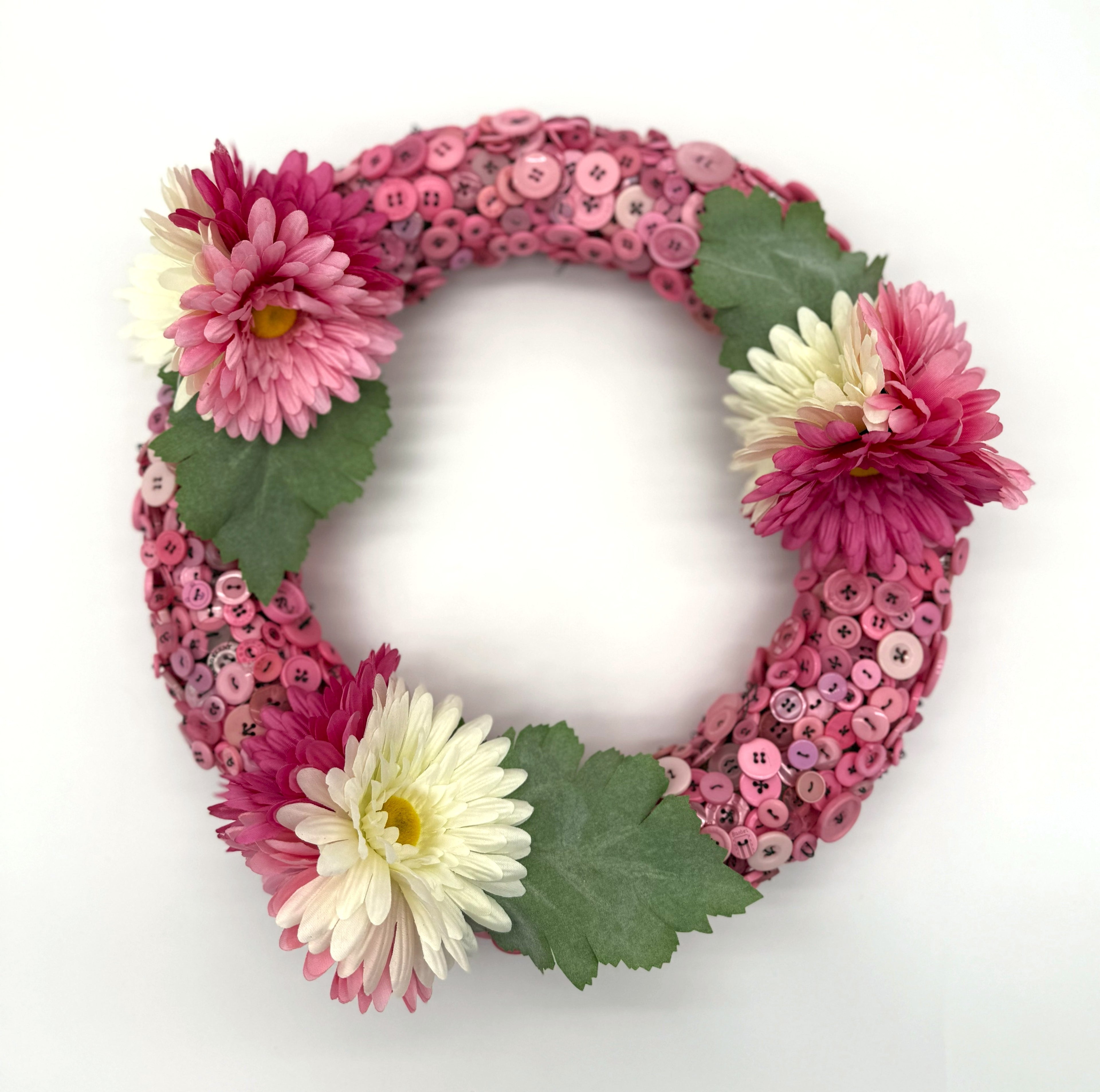 Decorative wreath with pink and white flowers and buttons on a white background