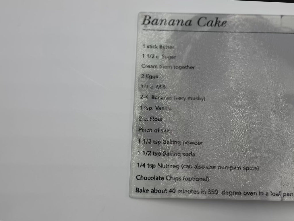 video showing textured glass cutting board with a banana cake recipe on it