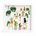 Collection of small items made of seaglass including plants and a cat figure on a white background