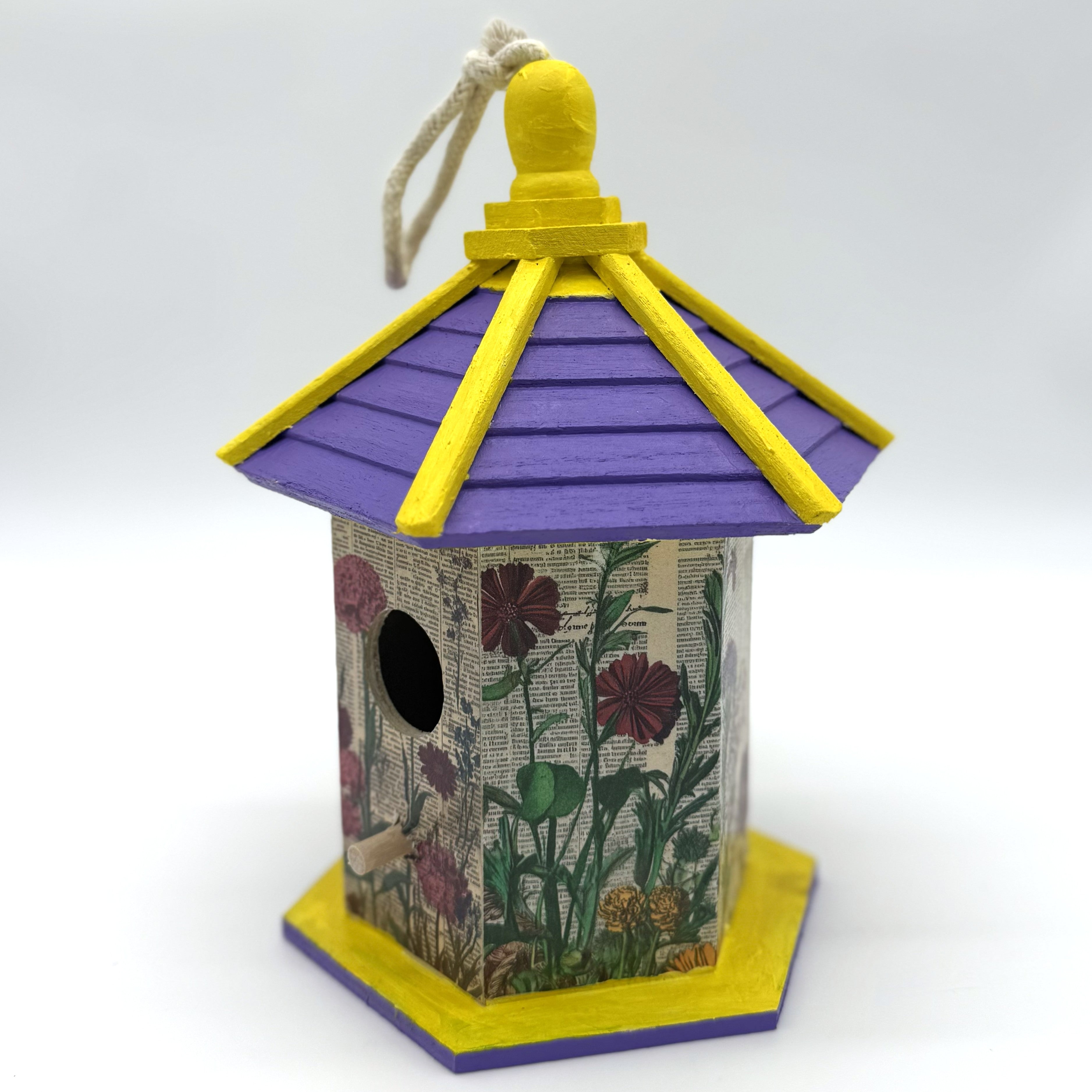 Decorative birdhouse with a purple roof and floral design on a white background