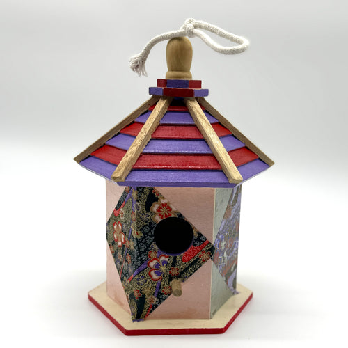 Decorative birdhouse with colorful roof and patterned body on a white background