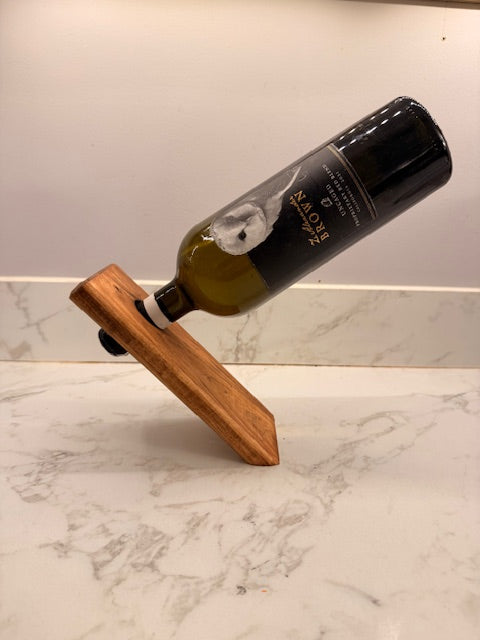 Wooden angled wine bottle holder with a wine bottle on a marble surface